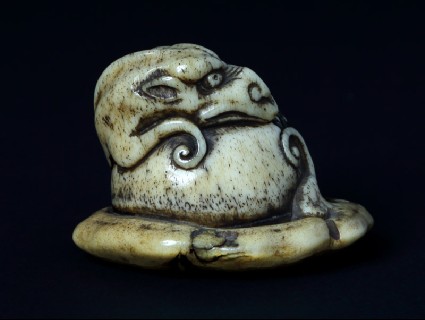 Netsuke in the form of a rain dragon coiled around a mokugyō, a Buddhist percussion instrumentfront