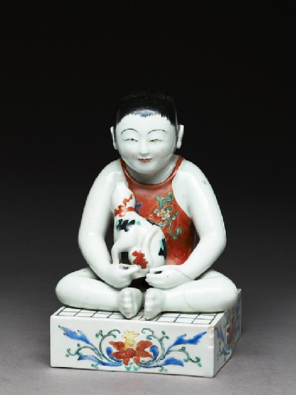 Figure of a boy seated on a shogi, or chess boardside