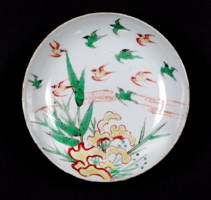 Dish with swallows flying over bamboofront