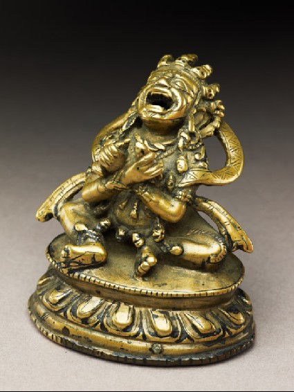 Seated figure of a male deity holding a bell and vajra, his head cocked back and mouth open, possibly an incense burner or pill dispenserside