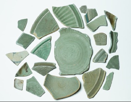 Group of greenware sherds with one blue and white fragmentfront