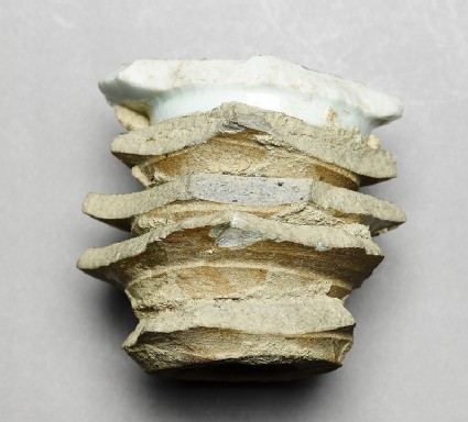 Stack of stoneware dishes surmounted by a porcelain dishside