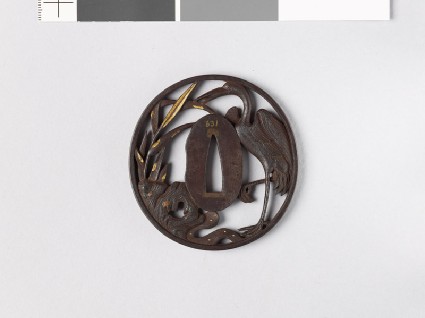 Tsuba depicting a crane standing among reeds, rocks, and waterfront