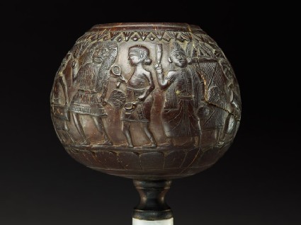Coconut bowl on stand with procession of figuresside
