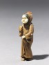 Netsuke in the form of a figure wearing a mask of Okame, a merry Shinto goddess (side)