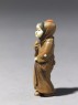 Netsuke in the form of a figure wearing a mask of Okame, a merry Shinto goddess (side)