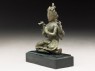 Seated figure of a crowned deity with four arms upon another figure (side)