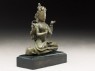 Seated figure of a crowned deity with four arms upon another figure (side)