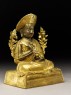Seated figure of a monk with two flowers, a sword, and scriptures (side)