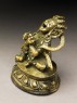 Seated figure of a male deity holding a bell and vajra, his head cocked back and mouth open, possibly an incense burner or pill dispenser (side)