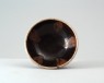 Black ware bowl with russet iron splashes and a white rim (oblique)