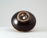 Black ware bowl with russet iron splashes and a white rim (oblique)